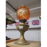 A brass oil lamp with amber glass shade.