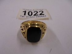 A yellow metal ring set black onyx, size R half. 68gms