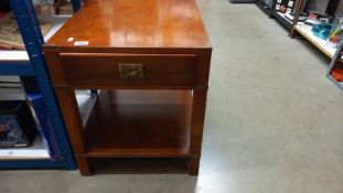 A dark wood stained table with brass corners and fittings plus a drawer