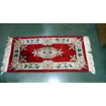 A red coloured rug - 143cm x 63cm (including tassels) COLLECT ONLY