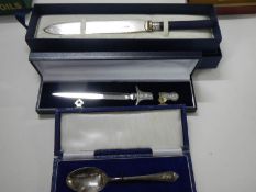 A boxed silver spoon, a boxed letter opener and a boxed bread knife.