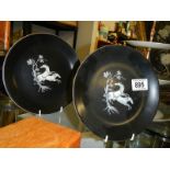 Two black display plates with transfer printed horses in white.