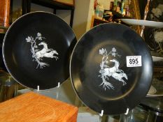 Two black display plates with transfer printed horses in white.