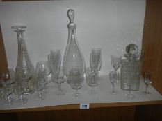 Three glass decanters and a quantity of drinking glasses.