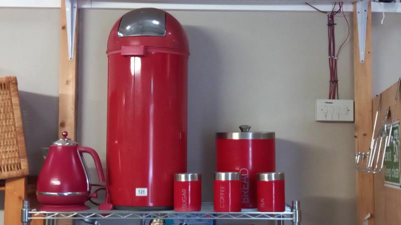 A Red kitchen waste bin storage container, kettle and storage canisters.