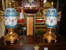 A good pair of 20th century porcelain lidded urns with gilded bases, COLLECT ONLY.