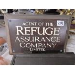 A wood and metal sign 'Agent of the Refuge Insurance Company Limited'.