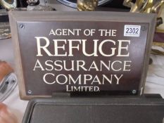 A wood and metal sign 'Agent of the Refuge Insurance Company Limited'.