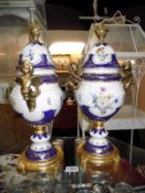 A pair of large continental porcelain gilded and painted cherubs surmounted urns height 47cm