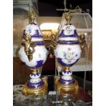 A pair of large continental porcelain gilded and painted cherubs surmounted urns height 47cm