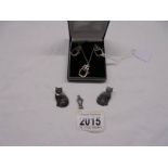 A silver cat pendant with matching earrings, another silver cat pendant and silver cat earrings.