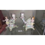 A pair of glazed continental porcelain cherub comport candlesticks