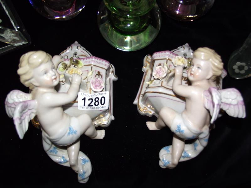 A pair of continental glazed bisque wall pockets of cherubs