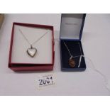 A silver and mother of pearl heart locket and an unmarked amber pendant.