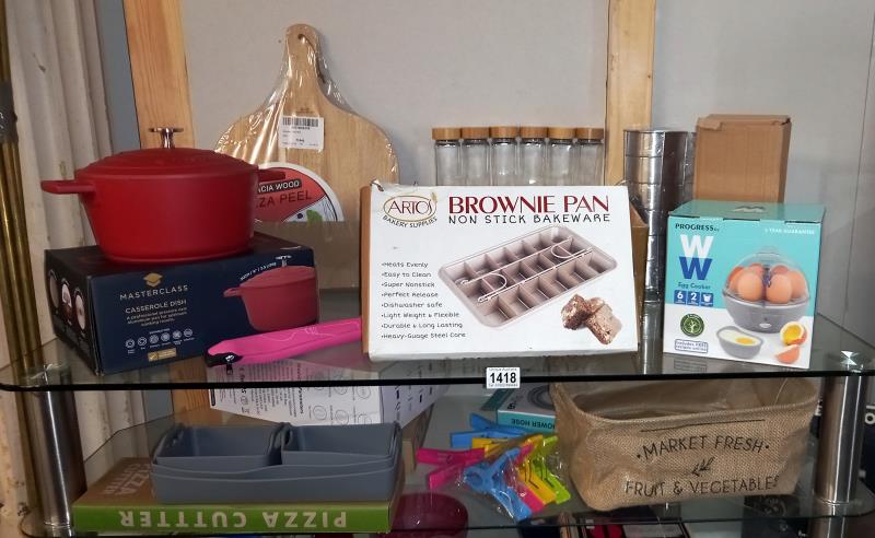 A quantity of 'new' kitchen items, includes casserole dish, baking trays, pizza slice, chopping