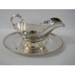 A silver plate gravy boat on tray.