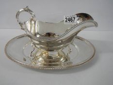 A silver plate gravy boat on tray.