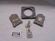 Three small silver photo frames and a silver pendant.