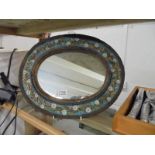 A small oval floral framed mirror.