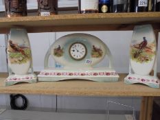 A three piece ceramic clock set decorated with birds.