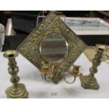 A brass framed mirror with candle sconces and a pair of brass candlesticks.