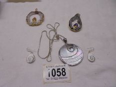 A mother of pearl pendant with matching earrings and two crystal pendants.
