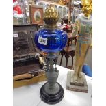 A Victorian oil lamp on spelter base and column with blue glass font. COLLECT ONLY.