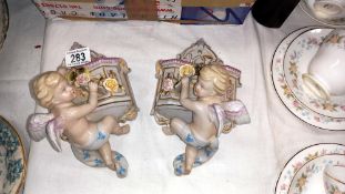A pair of continental bisque winged cherub wall pockets