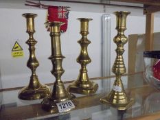 Four single brass candlesticks.