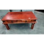 A dark wood stained rustic coffee table with iron fittings and 2 drawers