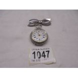 A Victorian ladies silver fob watch on a white metal bow pin.