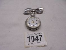 A Victorian ladies silver fob watch on a white metal bow pin.