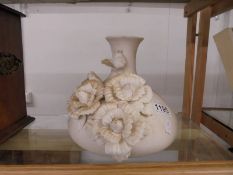 A white ceramic vase with applied flowers.
