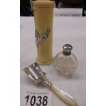 A silver topped scent bottle, a silver scoop and a pin pot with silver lettering.