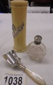 A silver topped scent bottle, a silver scoop and a pin pot with silver lettering.