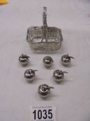 A silver plate basket and six silver plate place card holders in the shape of apples.