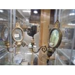 A pair of small brass wall mirrors with attached candle holders.
