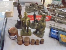 Two brass bells, two brass figures and a set of graduated measures.