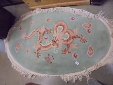 An oval Chinese rug featuring a dragon, COLLECT ONLY.