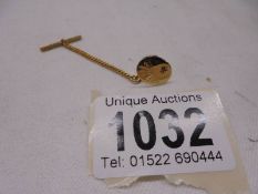 A Gent's tie pin, the front marked 9ct and set with a ruby, the back and safety chain not marked.