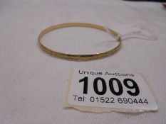 A 9ct gold engraved bangle, 6.6 grams.