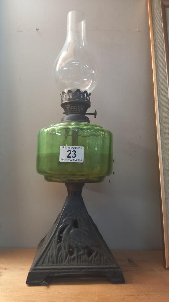 A Victorian oil lamp with green glass font and cast iron base