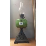 A Victorian oil lamp with green glass font and cast iron base