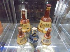 Four Wade Whisky bells and a Wade liquor bottle, with some contents.