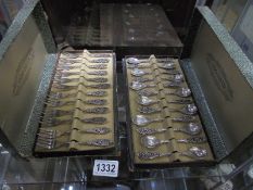 A cased set of twelve cake forks and a cased set of twelve tea spoons.