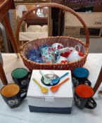 A wicker basket containing Ringtons mugs etc, plus a box of new 'luxury' mugs with spoons
