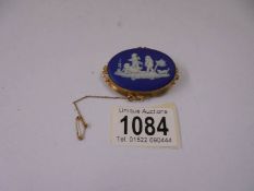 A Wedgwood Jasper ware brooch in 9ct gold mount and with safety chain.