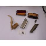 A cheroot holder in silver case, one other, a clay pipe and two cigarette lighters.