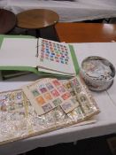 Three albums of world stamps and a tin of loose stamps.