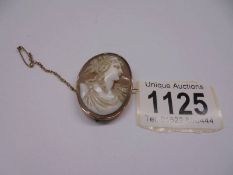 A shell cameo brooch of a female profile in a 9ct gold mount with safety chain.